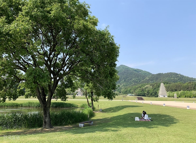 여행객이 미륵사지 잔디밭에서 한가로이 소풍을 즐기고 있다. 오른쪽 매끈한 탑이 1993년 복원한 동탑이다.