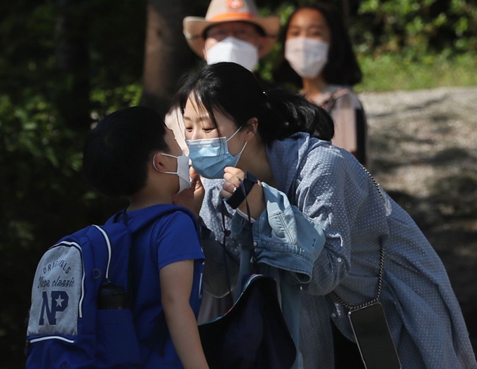 고등학교 2학년과 중학교 3학년, 초등학교 1∼2학년, 유치원생들의 등교 수업이 시작된 27일 오전 서울 성북구 월곡초등학교에서 한 학생이 엄마와 마스크 뽀뽀를 하고 있다. 연합뉴스