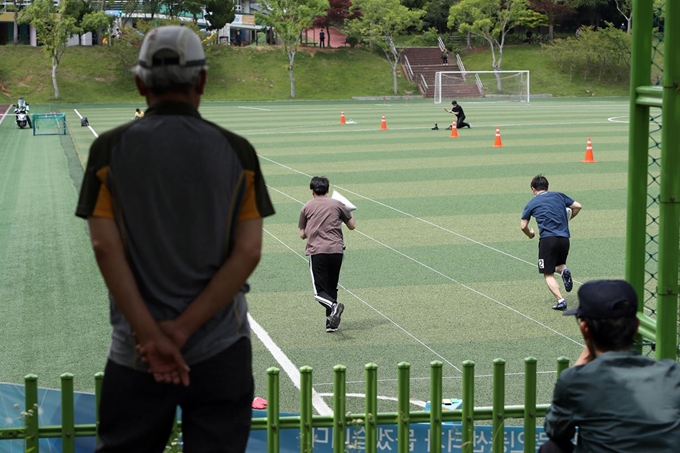 2일 오후 광주 북구 문화근린공원 인조잔디구장에서 가로환경관리원·청소기동반 신규채용 체력검정이 열려 시민들이 모래주머니를 들고 달리는 응시자를 바라보고 있다. 연합뉴스