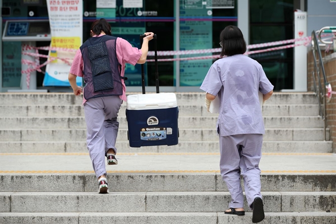 대구지역 '아동안전지킴이' 등 고위험군에 대한 신종 코로나바이러스 감염증(코로나19) 검사가 시작된 12일 오전 대구 달서구보건소에 마련된 선별진료소에서 근무를 마친 의료진이 흠뻑 젖은 모습으로 걸어가고 있다. 뉴스1