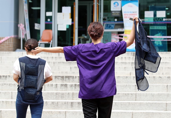 대구지역 '아동안전지킴이' 등 고위험군에 대한 신종 코로나바이러스 감염증(코로나19) 검사가 시작된 12일 오전 대구 달서구보건소에 마련된 선별진료소에서 근무를 마친 의료진이 흠뻑 젖은 모습으로 팔을 벌려 바람을 쐬고 있다. 뉴스1