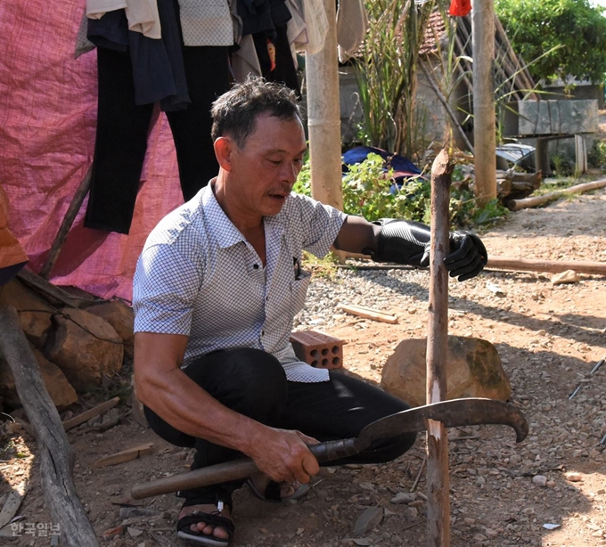 [저작권 한국일보] 베트남전 당시 매설된 지뢰로 왼팔과 눈을 잃은 트링딩테우씨가 지난달 26일 의수를 이용해 나무를 다듬고 있다. 동허이=정재호 특파원