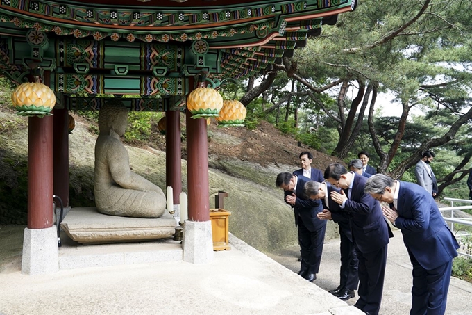 지난달 28일 김태년 더불어민주당, 주호영 미래통합당 원내대표와 오찬을 마친 문재인 대통령이 청와대 경내에 있는 석조여래좌상 앞에서 합장하고 있다. 청와대 제공