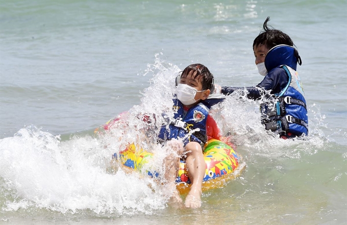 전국적으로 무더위가 찾아온 7일 부산 해운대해수욕장을 찾은 어린이들이 신종 코로나바이러스 감염증(코로나19) 예방을 위해 마스크를 착용한 채 물놀이를 즐기고 있다. 부산=뉴시스