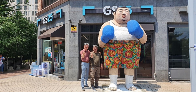 충북 진천군 진천읍 진천소방서 맞은편 쇼핑몰 앞길에 세워진 조형물 ‘힘센 척하는 놈’. 지난 8일 경기 양평군 국도변에 있던 것을 이곳으로 옮긴 뒤 작가 김원근(오른쪽)씨와 조형물을 매입한 이재룡씨가 작품 옆에서 손가락으로 하트 모양을 취하고 있다. 주민들은 “진천의 새 명물이 될 것”이라 반기고 있다. 한덕동 기자