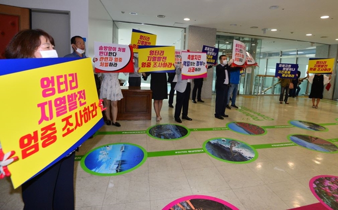 경북 포항지진 피해주민들이 12일 국무총리 소속 포항지진 진상조사위원회와 포항지역 지진관련 단체 대표들이 간담회를 갖는 포항시청 대회의실 앞에서 손팻말을 들고 배상과 관련자 처벌을 촉구하고 있다. 포항시 제공