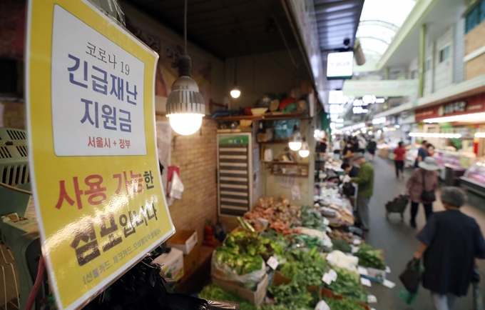 지난달 26일 오후 서울 망원시장이 시민들로 북적이는 가운데 한 가게에 ‘긴금재난지원금 사용 가능한 점포’라는 팻말이 붙어있다. 연합뉴스