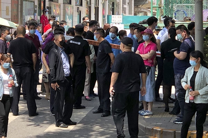 중국 수도 베이징의 한 스포츠 센터에 설치된 코로나19 검사소에서 공안과 보안요원의 통제 속에 시민들이 검사 차례를 기다리고 있다. 베이징=AP 연합뉴스