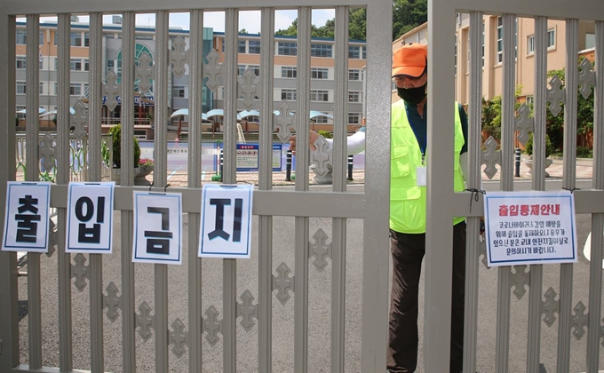 대전 서구 봉산초등학교 1학년 학생이 지역 신종 코로나바이러스 감염증 확진자와 접촉한 이력이 확인된 가운데 16일 오전 봉산초등학교에서 학교 관계자가 교문을 닫고 있다. 대전=뉴스1