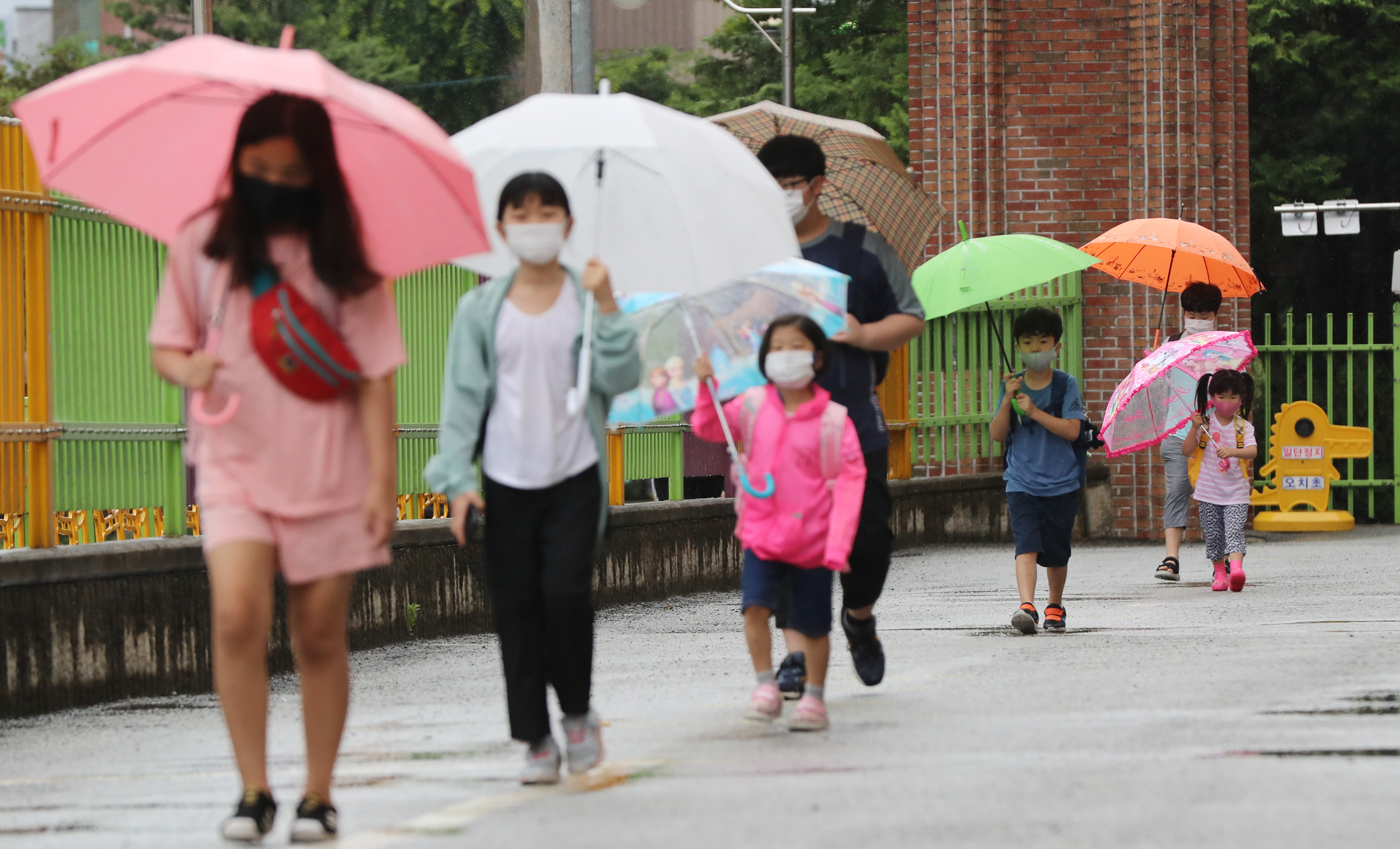 광주·전남지역에 비가 내린 18일 오전 광주 북구 오치초등학교에서 학생들과 병설유치원생들이 마스크를 쓰고 코로나19 예방 발열체크를 하기 위해 줄지어 이동하고 있다. 광주=연합뉴스