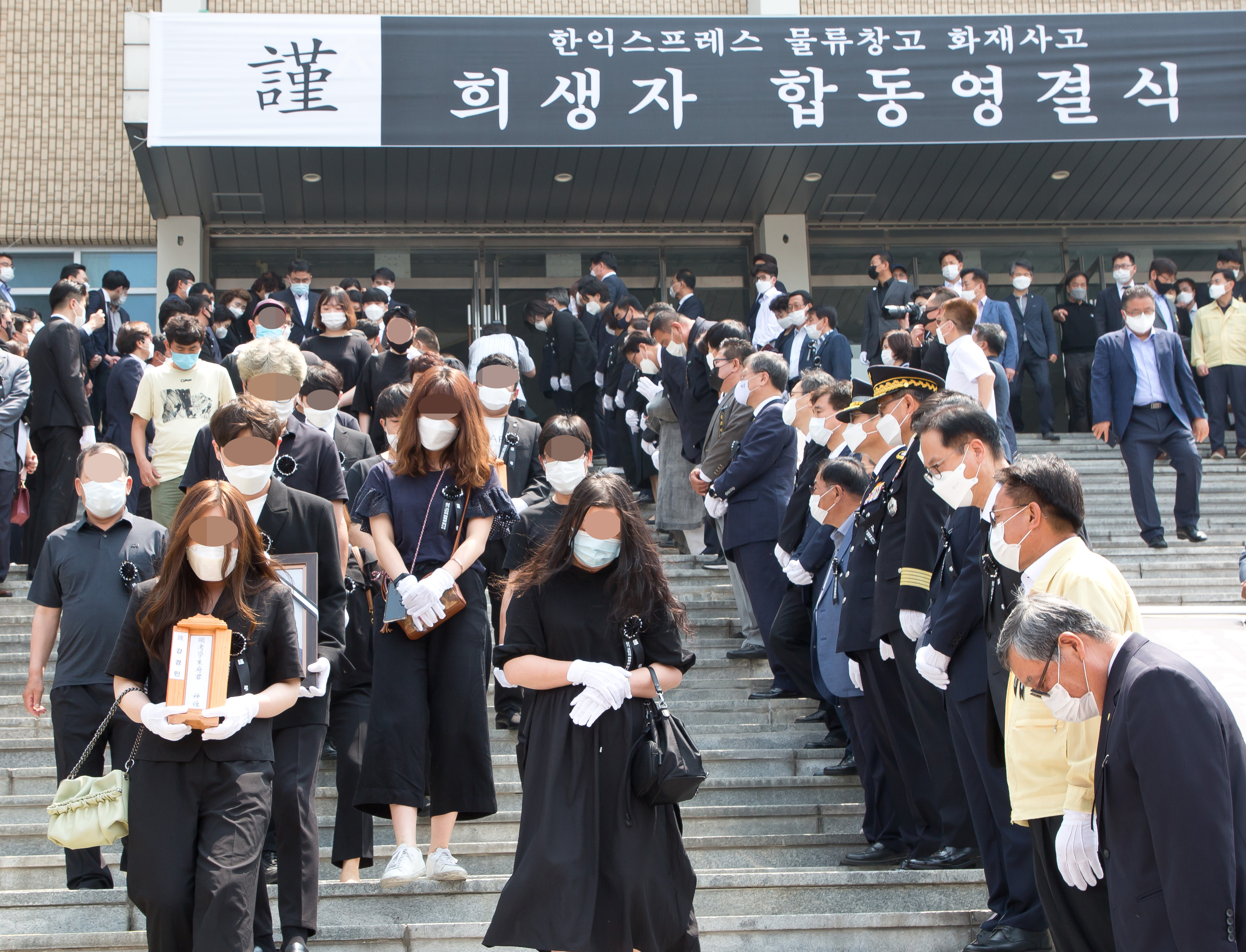 20일 오전 서희청소년문화센터에서 38명의 근로자가 숨진 경기도 이천 한익스프레스 물류창고 화재 사고 희생자들의합동 영결식 후 영정을 든 유가족이 계단을 내려 오고 있다. 뉴시스