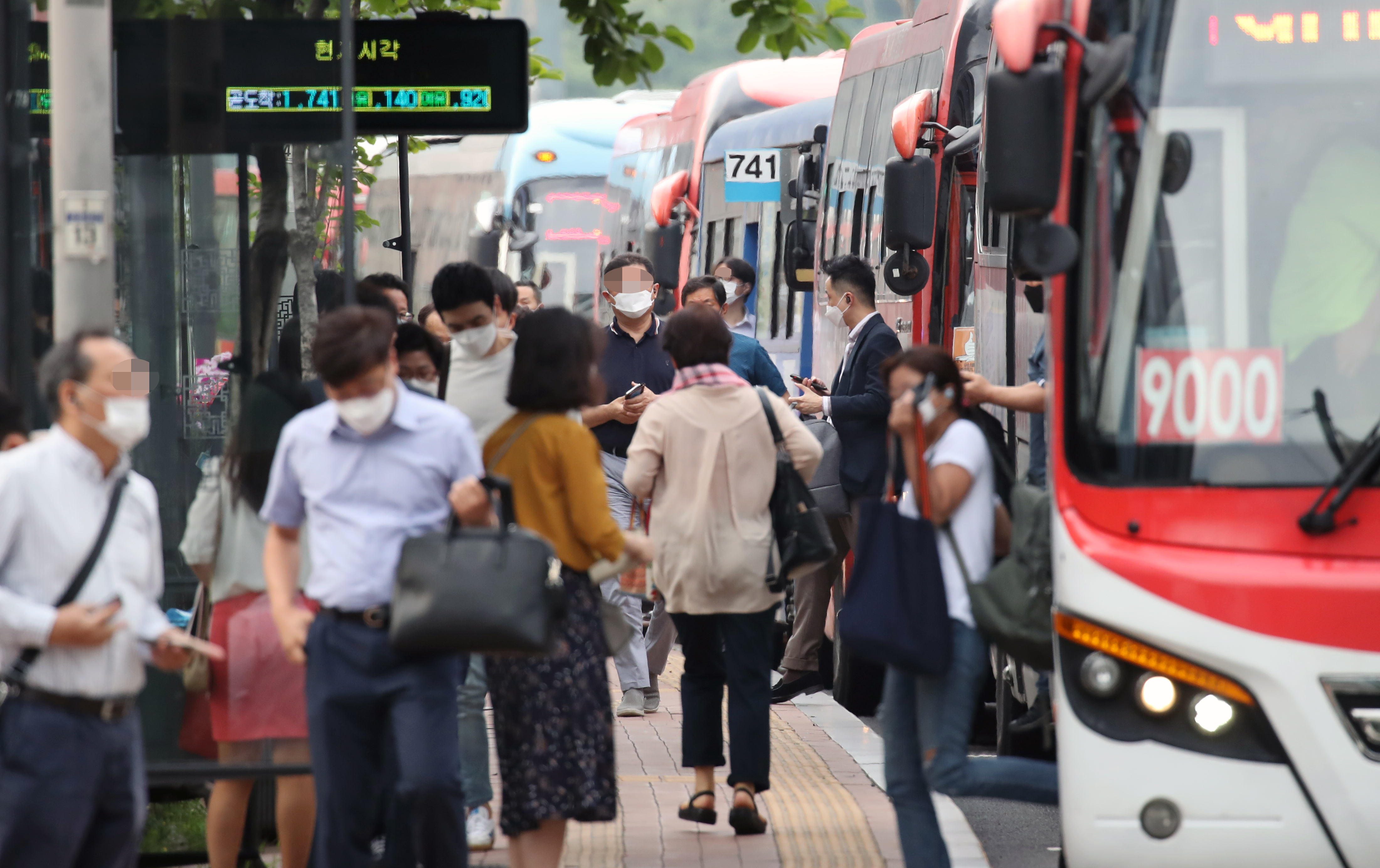 지난 15일 서울 중구의 한 버스 정류장에서 마스크를 쓴 시민들이 출근을 서두르고 있다. 연합뉴스