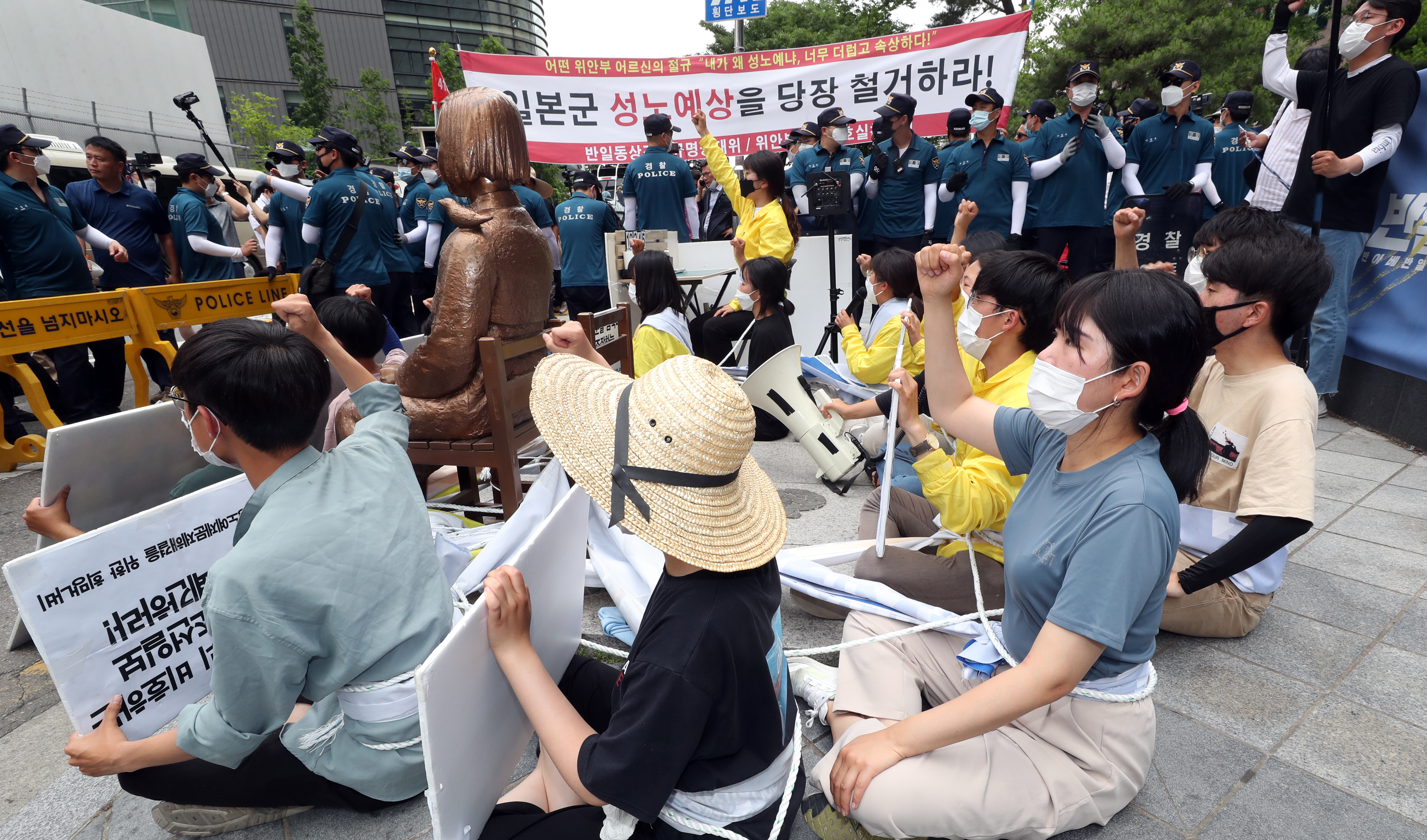 대학생단체 반아베반일청년공동행동 회원들이 23일 서울 종로구 옛 일본대사관 건너편에서 소녀상과 몸에 밧줄을 묶고 구호를 외치고 있다. 뉴스1