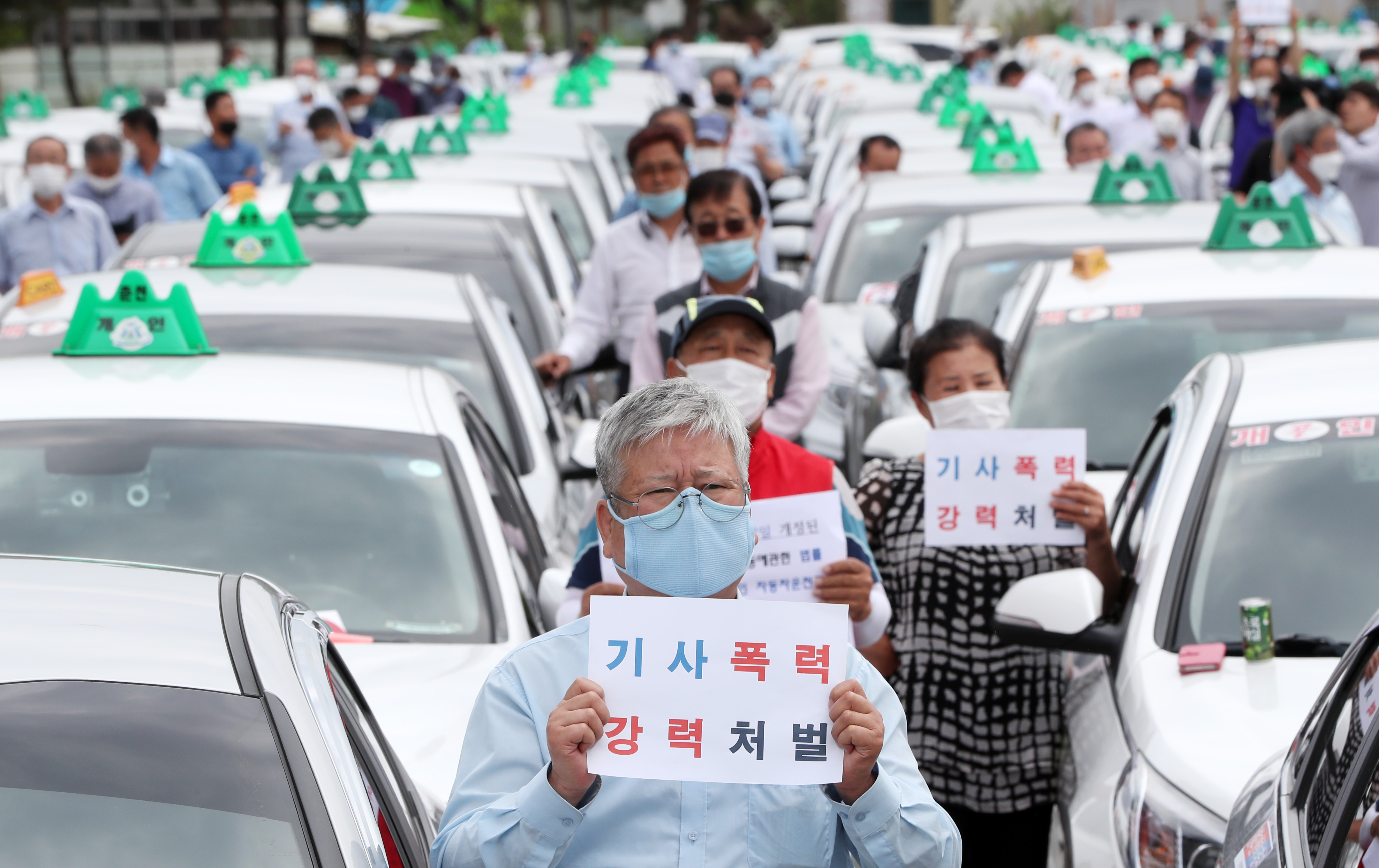 19일 강원 춘천시 운수종사자 휴게시설 앞에서 지역 택시 종사자 300여 명이 최근 춘천에서 일어난 택시기사 폭행 사건 피의자에 대한 구속 수사와 엄벌을 촉구하는 손팻말을 들고 있다. 연합뉴스