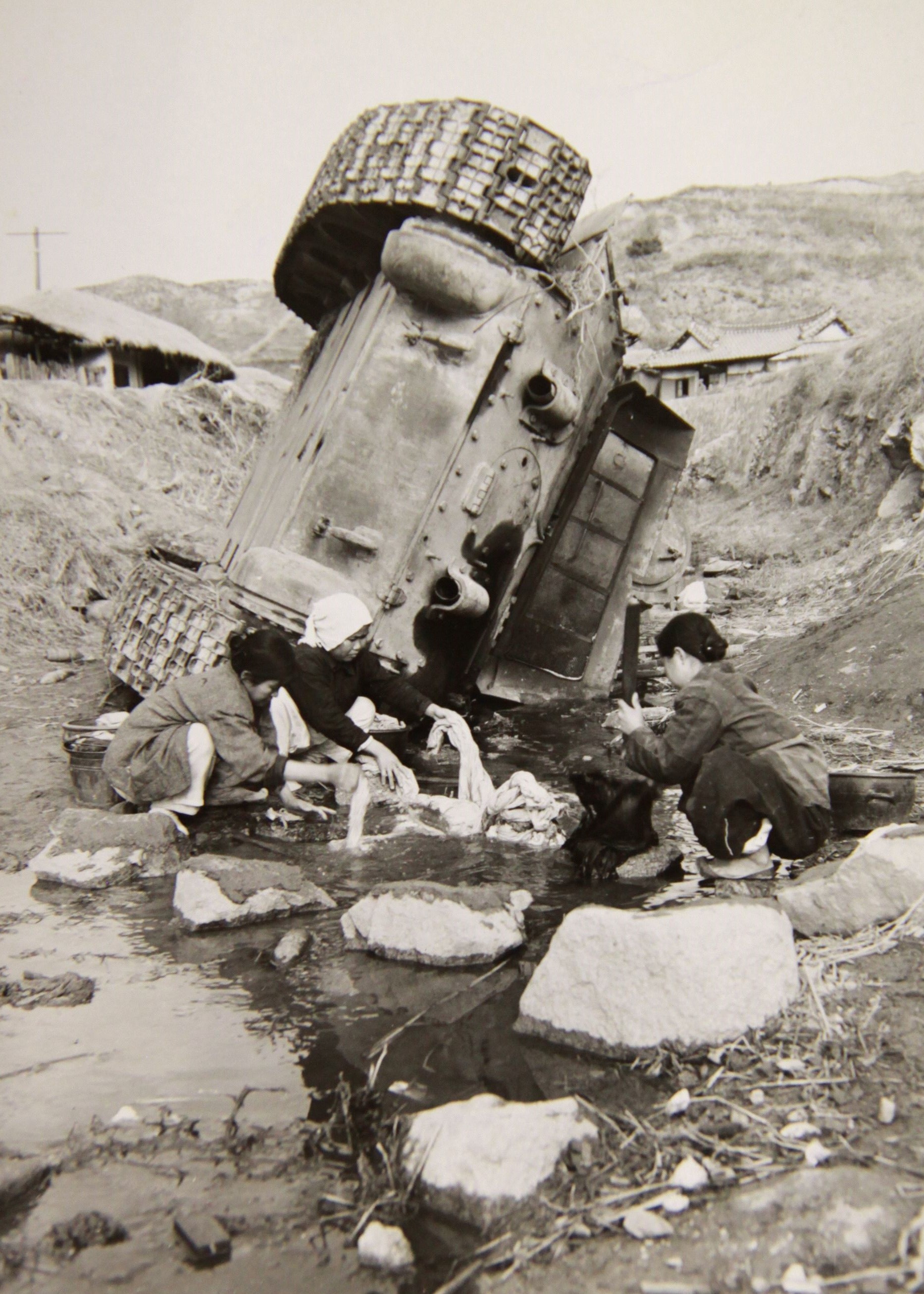 1951년 1월 8일, 미군 사령부 근방에서 빨래를 하고 있는 조선인 여성들. 이들의 뒤로 거꾸로 처박힌 러시아제 T-34 탱크가 보인다. 미국 국립문서기록관리청(NARA) 제공