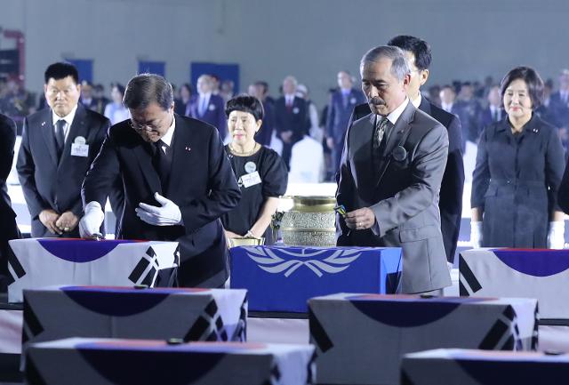 문재인 대통령과 해리 해리스(문 대통령 오른쪽) 주한미군대사를 비롯한 참석자들이 25일 경기 성남시 서울공항에서 열린 6·25 전쟁 70주년 행사에서 국군 전사자 유해함에 6·25 참전 기장을 수여하고 있다. 연합뉴스?