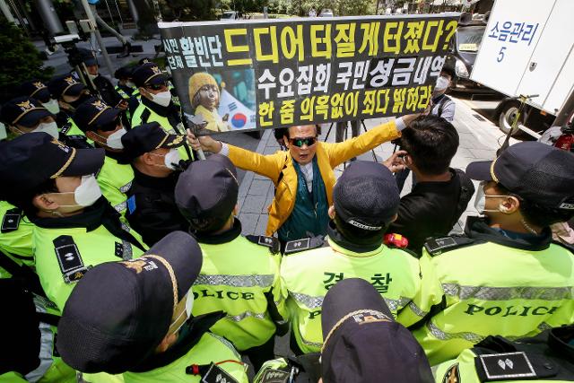 홍정식 활빈단 대표가 지난달 13일 오후 서울 종로구 옛 일본대사관 앞에서 열린 일본군 위안부 문제 해결을 위한 정기 수요집회에 나타나 정의기억연대를 비판하는 현수막을 펼쳐 경찰의 통제를 받고 있다. 뉴시스