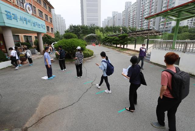 11일 오전 광주 서구의 한 중학교에 마련된 국가직 공무원 9급 필기시험장에 수험생들이 줄을 서 입장하고 있다. 최근 코로나19 확산세가 이어진 광주에서는 이날 1만2,121명이 지원한 국가직 공무원 9급 필기시험이 27개 시험장, 654개 시험실에서 치러진다. 연합뉴스