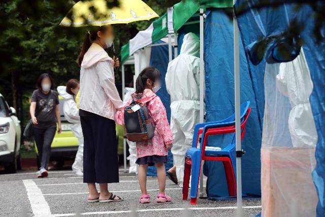 13일 오후 신종 코로나바이러스 감염증 선별 진료소가 차려진 경기 수원시 영통구의 한 유치원에서 원생과 보호자들이 검사 순서를 기다리며 줄을 서 있다. 연합뉴스