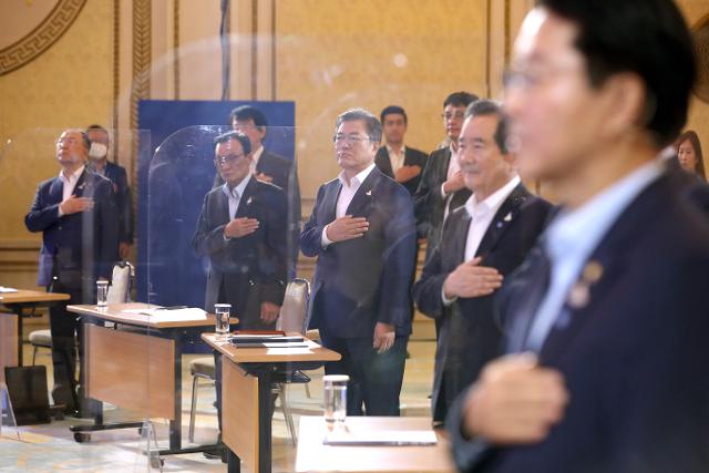 문재인 대통령이 14일 청와대 영빈관에서 열린 '한국판 뉴딜 국민보고대회'에서 국기에 경례하고 있다. 연합뉴스