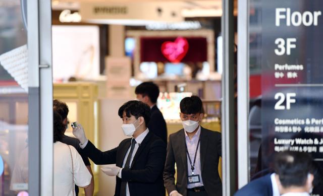 신라면세점이 면세 재고상품 판매를 시작한 21일 오전 서울 중구 신라면세점 서울점에서 관계 직원이 입장하는 고객들의 체온을 재고 있다. 홍인기 기자