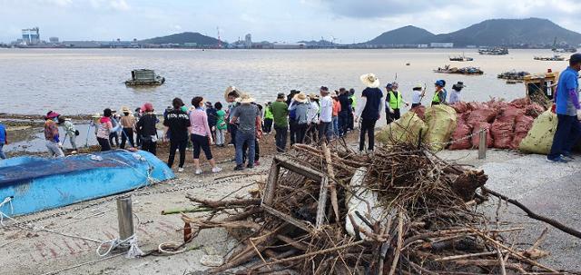 목포평화광장 앞바다에 몰려든쓰레기를 목포시청 공직자와 자원봉사자들이 수거하고 있다.