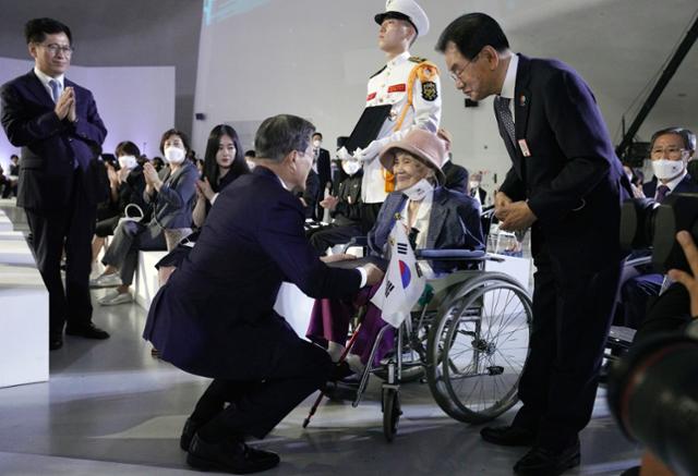 문재인 대통령이 15일 오전 서울 동대문디자인플라자에서 열린 제75주년 광복절 경축식에서 독립유공자 고 최사진 씨에게 대통령표창을 추서한 뒤 배우자 박명순 씨에게 증서를 전달하고 있다. 연합뉴스