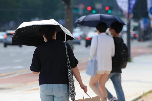 서울 전역에 폭염경보가 발효된 17일 오후 서울 종로구 광화문 앞에서 양산을 쓴 시민들이 발걸음을 옮기고 있다. 뉴시스