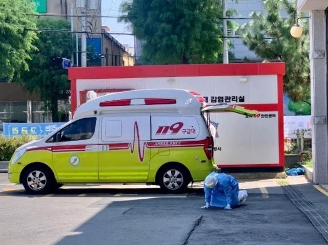 20일 전북 전주 시내 한 소방서 앞에서 방호복을 입은 의료진이 땅바닥에 엎드려 힘들어하고 있다. 해당 사진은 이날 각종 온라인 커뮤니티 사이트에 올라왔다. 온라인 커뮤니티사이트 캡처