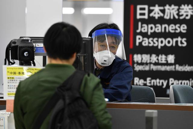 지난 3월 도쿄의 관문인 나리타국제공항 검역구역에서 출입국 관리를 담당하는 직원이 페이스쉴드와 마스크를 착용하고 입국하는 승객을 맞고 있다. 지바=AFP 연합뉴스