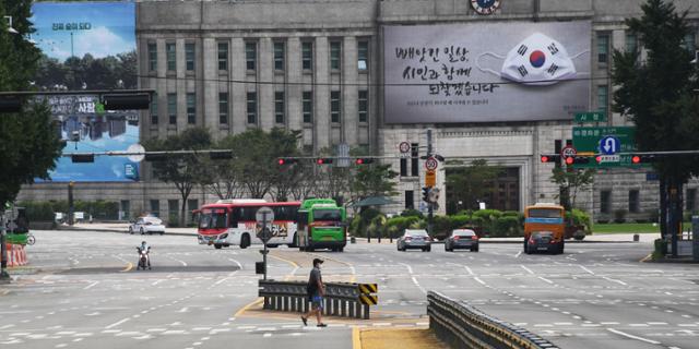 수도권을 중심으로 코로나19 확진자가 급증함에 따라 정부가 '사회적 거리두기' 2단계 방역강화 조치를 전국으로 확대한 가운데 휴일인 23일 오전 한 시민이 서울시청 인근 횡단보도를 건너고 있다.20200823 고영권 기자