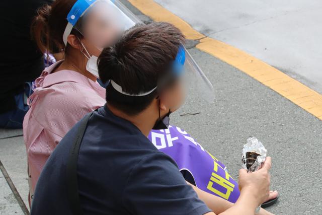 27일 오전 대구 중구 동인동 대구시청 본관 앞에서 열린 집회에서 일부 집회 참가자가 마스크를 턱까지 내린 상태로 음식을 먹고 있다. 뉴스1