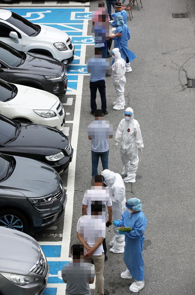 지난 27알 광주 동구선별진료소에서 의료진이 코로나19 검사를 받는 시민들의 접수를 돕고 있다. 연합뉴스