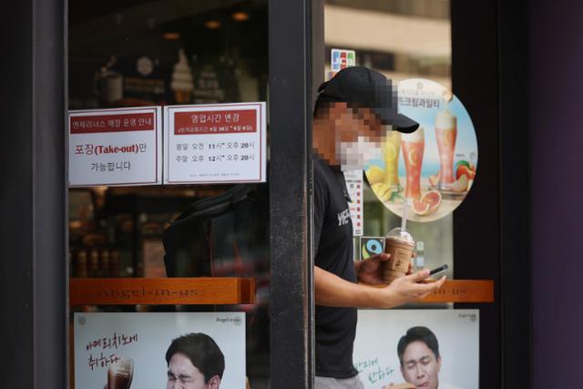 '사회적 거리두기 2.5단계'가 실시되며 수도권 프렌차이즈 커피 전문점 매장 내 이용이 금지된 30일 오후 서울 종로구의 한 커피 전문점에서 손님이 포장한 음료를 들고 나오고 있다. 연합뉴스