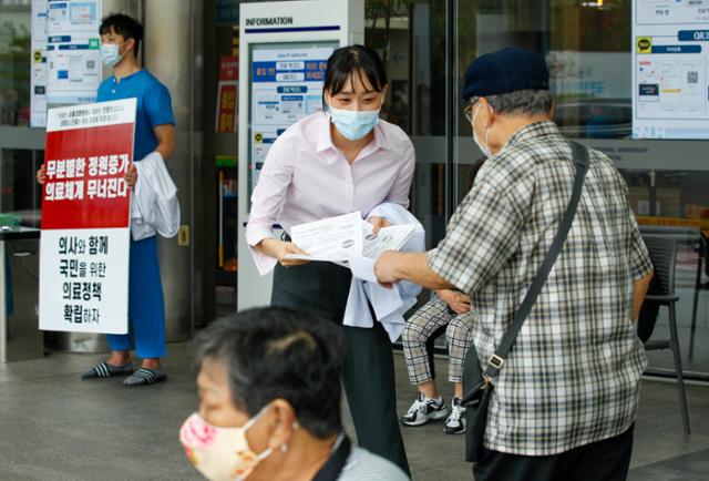 전공의들이 무기한 파업을 지속하기로 한 31일 서울 종로구 서울대병원 본관 앞에서 한 의료진이 정부가 추진하고 있는 의대 정원 확대, 공공의대 설립 반대 내용의 유인물을 배포하고 있다. 뉴스1