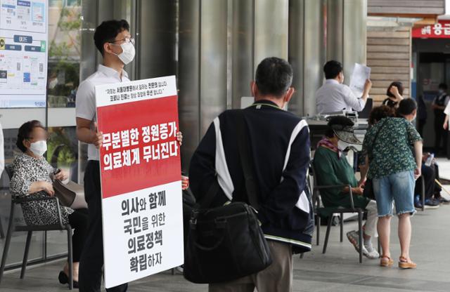 의료계가 의대정원 확대, 공공의대 설립 등 주요 정책 철회를 촉구하며 집단휴진을 이어가던 1일 서울 종로구 서울대병원 본관 앞에서 한 전공의가 정부의 의료정책에 반대하는 피켓을 들고 있다. 뉴스1