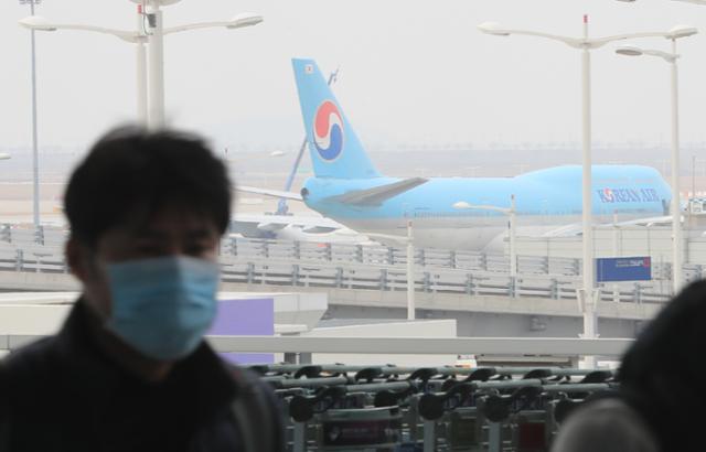 인천국제공항 제2여객터미널 계류장에 주기된 여객기 앞으로 마스크를 쓴 승객이 이동하고 있다. 인천=뉴스1