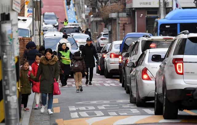 서울 한 초등학교 인근 어린이보호구역에서 어린이들이 차량을 피해 등교하고 있다. 한국일보 자료사진