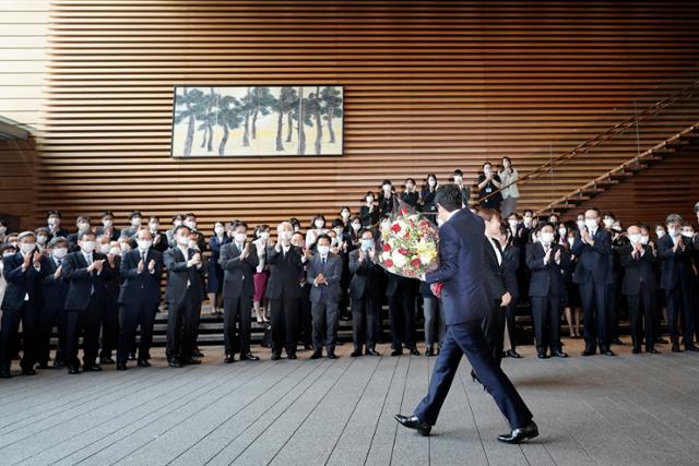 아베 신조 일본 총리가 16일 도쿄 총리공관을 떠나기 전 꽃다발을 받고 인사하고 있다. AP 연합뉴스