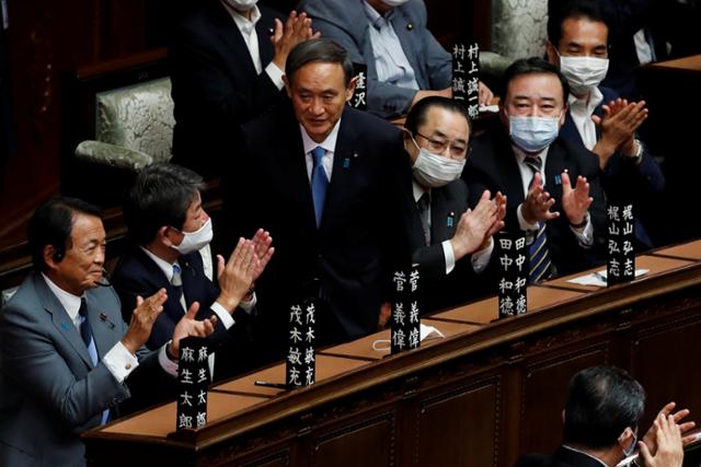 스가 요시히데(가운데) 일본 신임 총리가 16일 오후 중의원에서 열린 지명투표에서 과반을 획득해 제99대 총리로 선출되자 자리에서 일어나 의원들에게 인사하고 있다. 도쿄=로이터 연합뉴스