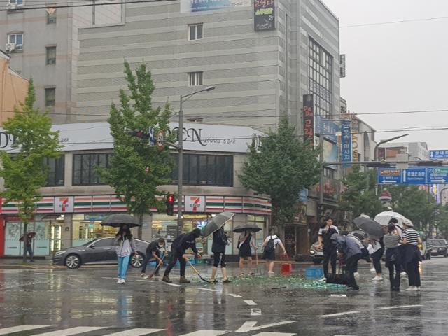 경북 포항 세명고등학교 학생들이 지난 7월 23일 포항시 북구 죽도동 젊음의 거리 인근 교차로에서 장맛비를 맞으며 도로 위에 쏟아진 술병을 치우고 있다. 포항=김정혜 기자