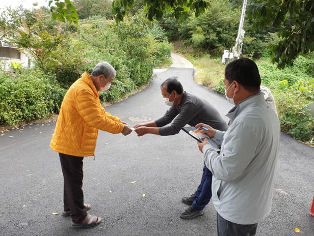 영동군 양강면 구강리 마을 이장(가운데)이 23일 마을 어르신에게 재난지원금을 전달하고 있다. 영동군 제공