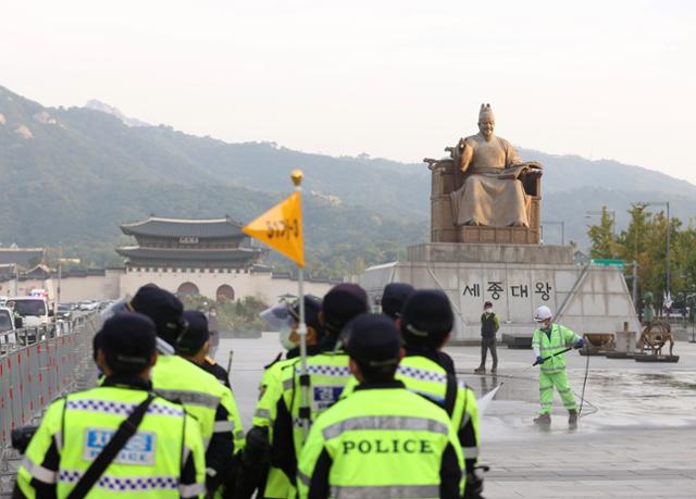 29일 오전 서울 종로구 광화문광장에 차려졌던 '고(故) 백선엽 장군 분향소'가 철거된 자리에서 구청 청소행정과 관계자가 물청소를 하고 있다. 서울시는 이날 오전 분향소 텐트와 집회 물품 등을 강제 철거했다. 연합뉴스