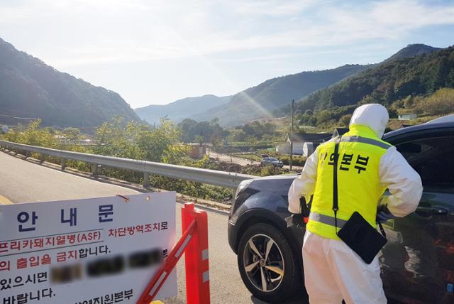 아프리카돼지열병(ASF)이 발생한 9일 오전 강원 화천군 서면의 농가 진입로에서 방역요원이 출입차량의 운전자의 신원을 확인하고 있다. 뉴스1