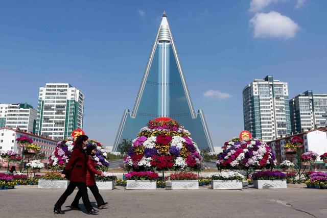 평양 류경호텔 앞에서 평양 시민들이 꽃으로 장식된 거리를 걷고 있다. 평양=AP 뉴시스