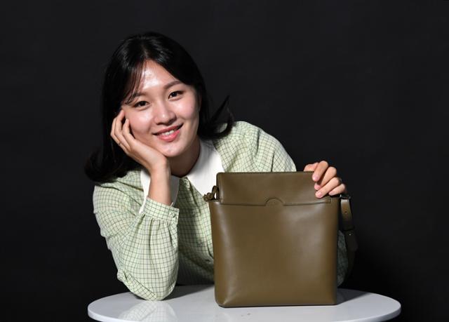 a-woman-holding-her-chin-while-showing-the-bag-she-made