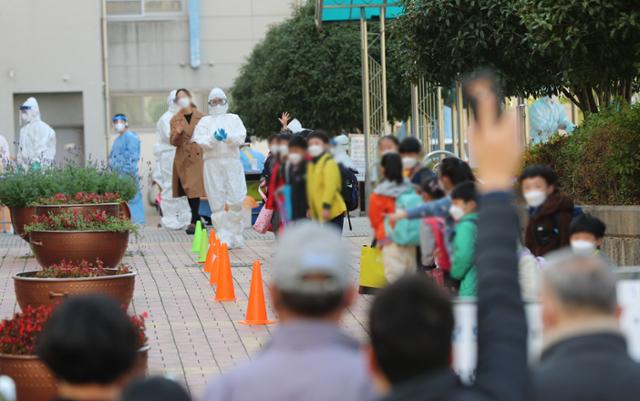 16일 오전 광주 북구의 한 초등학교에 마련된 이동식 선별진료소에서 학생들이 코로나19 전수 검사를 받고 있고, 학부모들은 교문 밖에서 자녀들이 나오길 애타게 기다리고 있다. 이날 광주에서는 전남대병원에서 시작된 코로나19 확산이 자녀들이 다니는 학교에까지 이어졌다. 연합뉴스