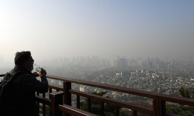 주말인 15일 오전 서울 남산에서 한 시민이 물을 마시며 미세먼지로 뿌연 도심시내를 바라보고 있다. 홍인기 기자