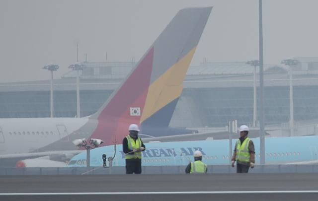 대한항공의 아시아나항공 인수 발표가 하루 지난 17일 오후 인천국제공항 제4활주로 공사현장 뒤로 대한항공과 아시아나항공 여객기들이 세워져 있다. 연합뉴스