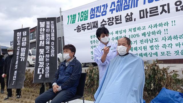 18일 전남 구례군 구례읍 오일시장에서 섬진강 구례 수해 대책위 대표들이 책임자 처벌과 사과 등을 요구하며 삭발을 하고 있다. 뉴스1(독자제공)